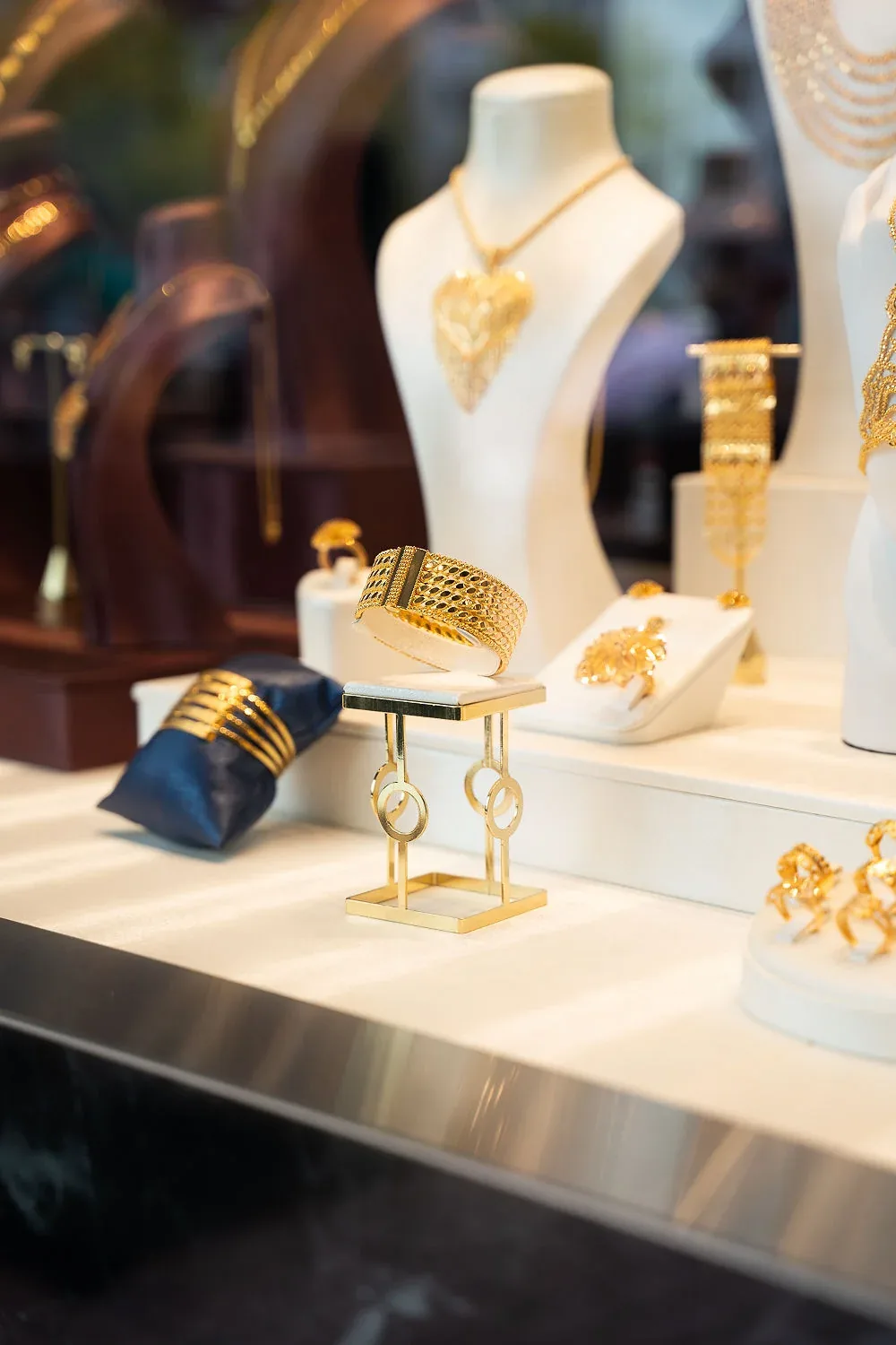 Schaufenster mit Goldcolliers und Armreifen auf weißen Büsten